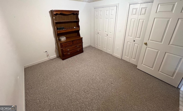 unfurnished bedroom featuring two closets and carpet floors