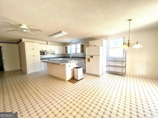 kitchen featuring a kitchen island, white cabinetry, hanging light fixtures, white fridge with ice dispenser, and ceiling fan with notable chandelier