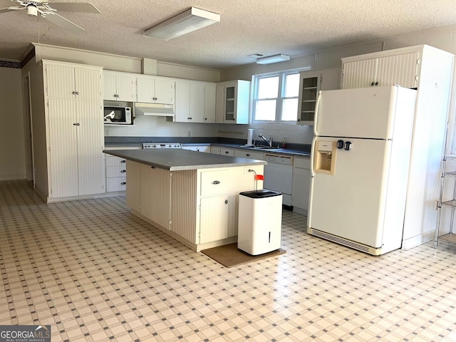 kitchen featuring white appliances, a textured ceiling, a center island, sink, and ceiling fan