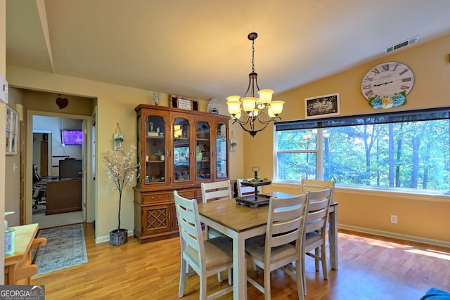 dining space with light wood-type flooring, lofted ceiling, and a chandelier