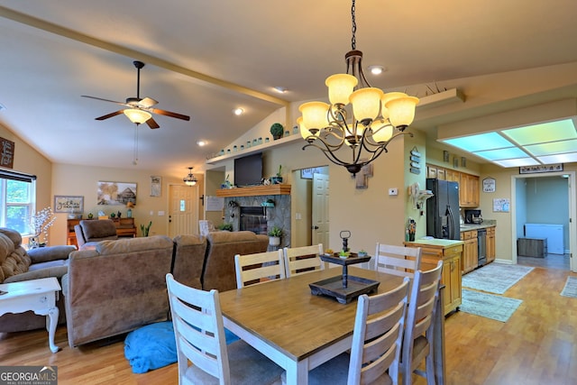 dining room featuring vaulted ceiling, ceiling fan with notable chandelier, and light wood-type flooring