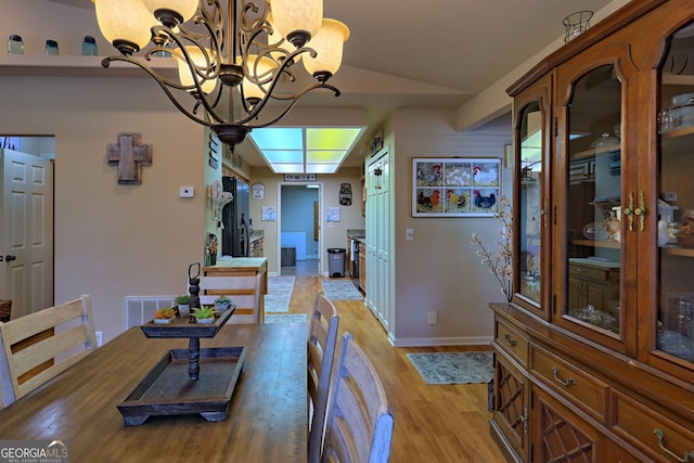 dining area featuring light hardwood / wood-style floors, a notable chandelier, and vaulted ceiling