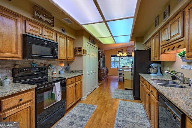 kitchen featuring black appliances, light stone counters, sink, lofted ceiling, and light hardwood / wood-style floors