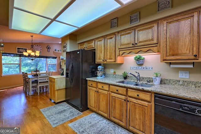 kitchen featuring black appliances, light hardwood / wood-style floors, sink, a chandelier, and lofted ceiling