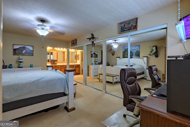 carpeted bedroom with a textured ceiling, ceiling fan, and two closets