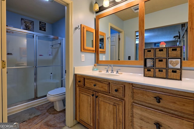 bathroom with toilet, a shower with door, and vanity