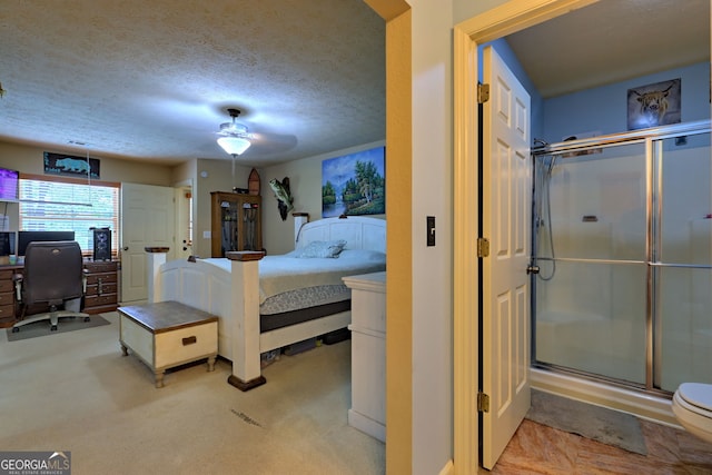 bedroom featuring a textured ceiling, light colored carpet, and ceiling fan