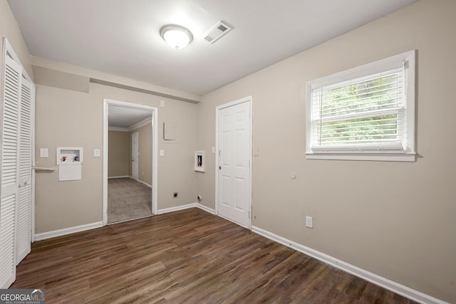 unfurnished bedroom featuring crown molding and dark wood-type flooring