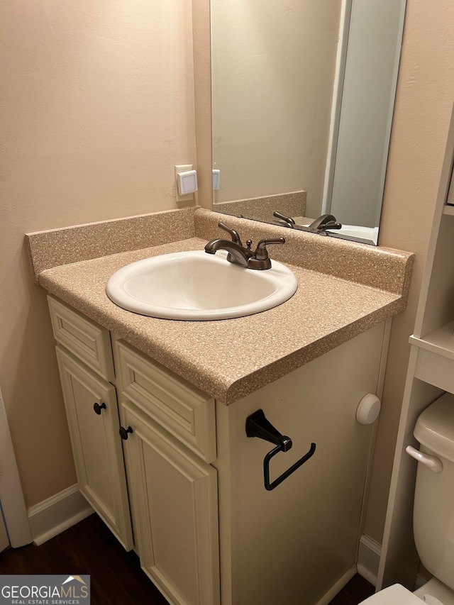 bathroom with vanity, toilet, and hardwood / wood-style floors