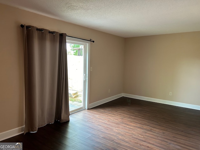 spare room with dark wood-type flooring and a textured ceiling