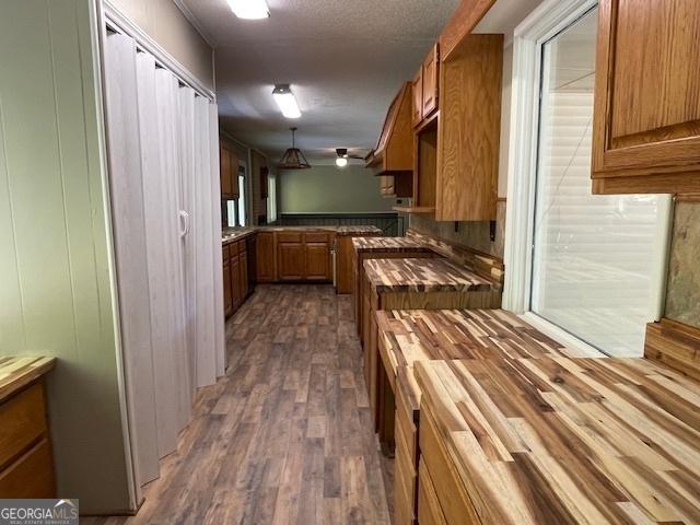 kitchen with dark hardwood / wood-style floors, butcher block counters, hanging light fixtures, and a textured ceiling