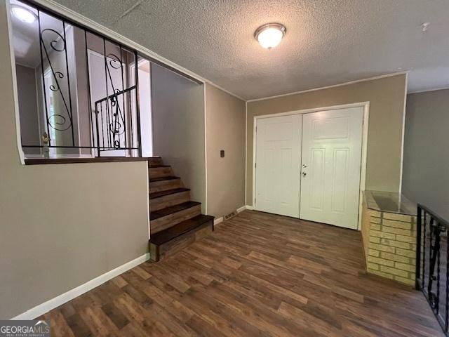 foyer entrance with dark hardwood / wood-style floors and a textured ceiling