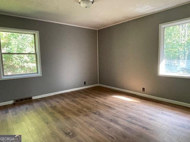 spare room with hardwood / wood-style flooring, crown molding, and a textured ceiling