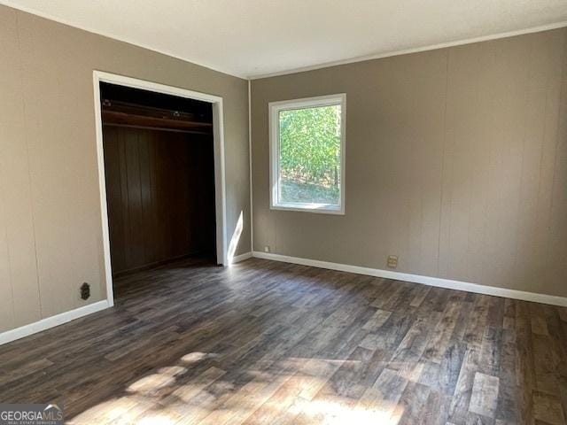 unfurnished bedroom with dark hardwood / wood-style flooring and a closet