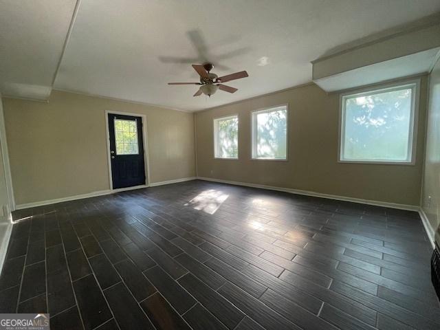 spare room featuring dark wood-type flooring, ceiling fan, and a wealth of natural light