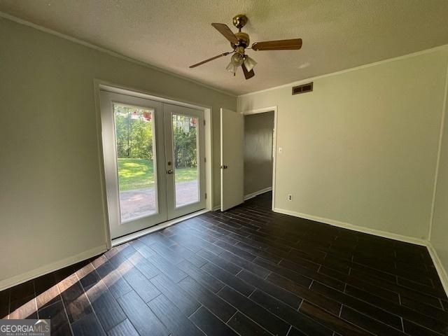 unfurnished room with dark hardwood / wood-style floors, ornamental molding, french doors, and a textured ceiling