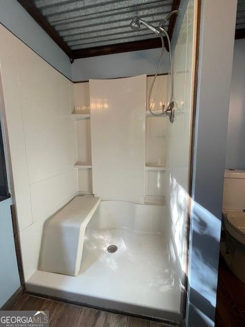 bathroom with walk in shower, toilet, and hardwood / wood-style floors