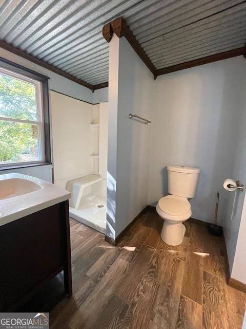 bathroom with toilet, a shower, wood-type flooring, ornamental molding, and vanity