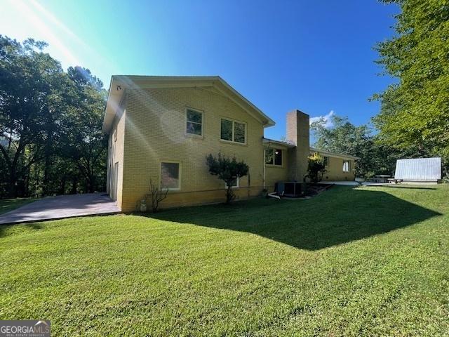 back of property with a yard and central AC unit