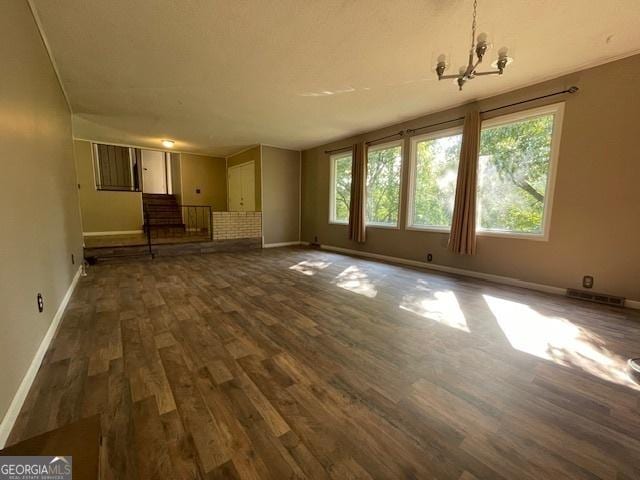 unfurnished living room featuring dark wood-type flooring and an inviting chandelier