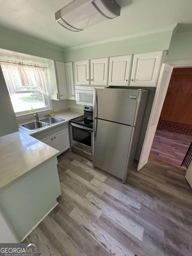 kitchen featuring light wood-type flooring, white cabinets, appliances with stainless steel finishes, and sink