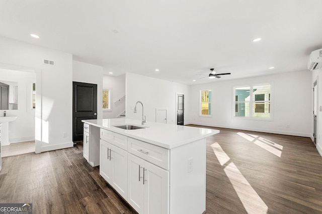 kitchen featuring white cabinets, sink, ceiling fan, an island with sink, and dark hardwood / wood-style flooring