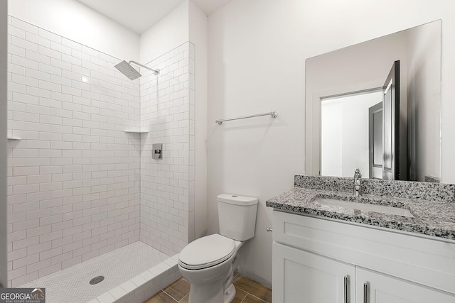 bathroom with toilet, vanity, and tiled shower