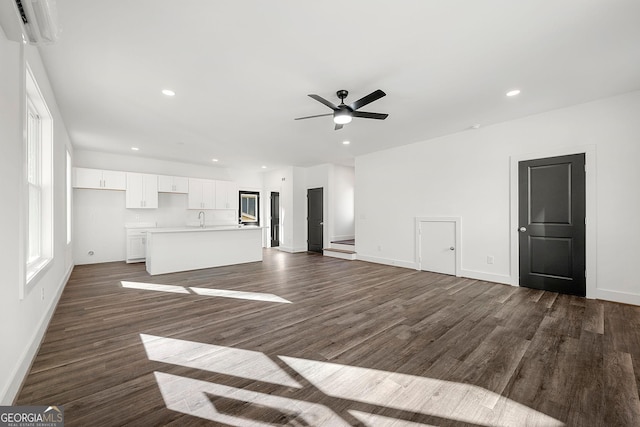 unfurnished living room featuring ceiling fan, dark hardwood / wood-style flooring, sink, and a wall mounted AC