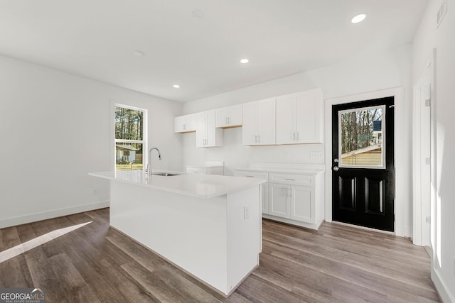 kitchen with hardwood / wood-style flooring, a center island with sink, white cabinets, and sink