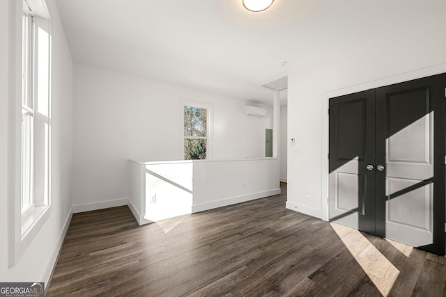 unfurnished room featuring an AC wall unit, electric panel, and dark hardwood / wood-style floors