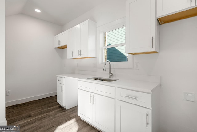 kitchen with lofted ceiling, white cabinetry, sink, and dark wood-type flooring