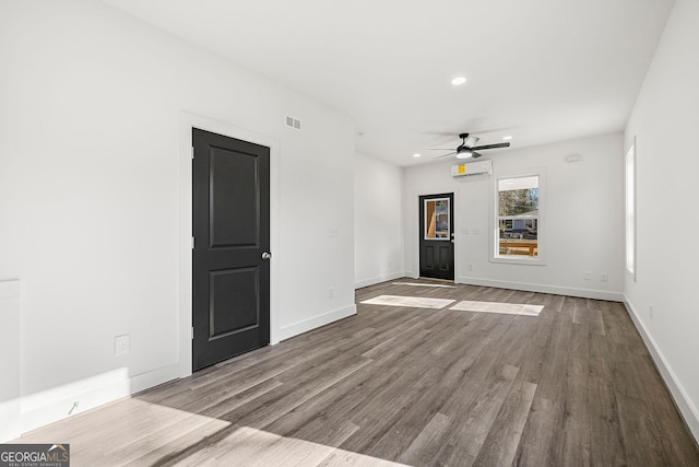 spare room with light hardwood / wood-style floors, an AC wall unit, and ceiling fan