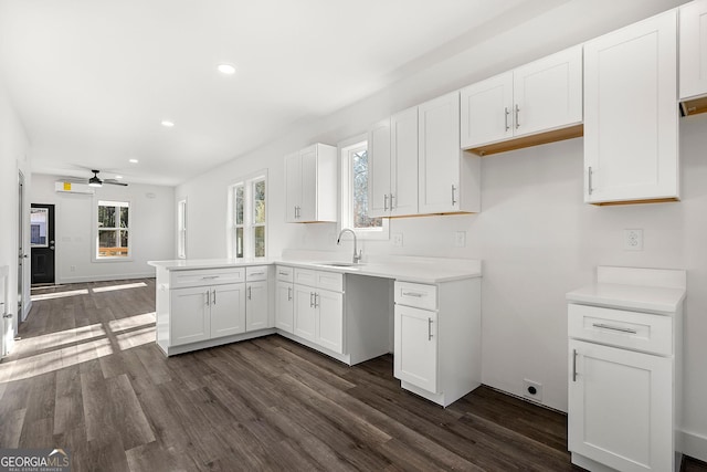 kitchen with white cabinetry, ceiling fan, sink, dark wood-type flooring, and kitchen peninsula