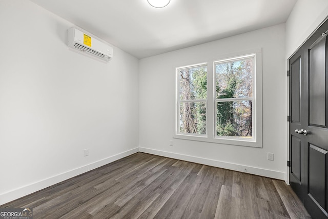 unfurnished room with wood-type flooring and a wall unit AC