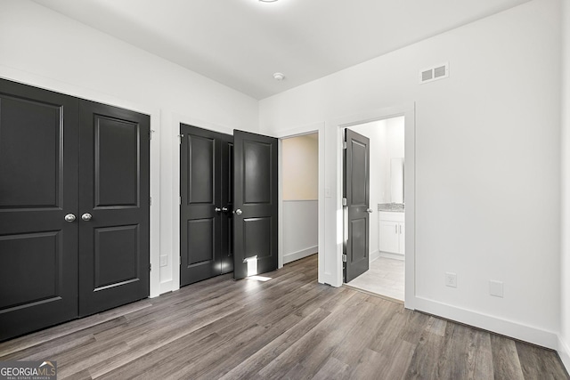 unfurnished bedroom featuring connected bathroom and light hardwood / wood-style flooring