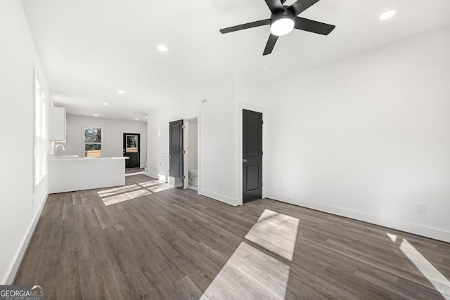 unfurnished living room featuring dark hardwood / wood-style floors, ceiling fan, and sink