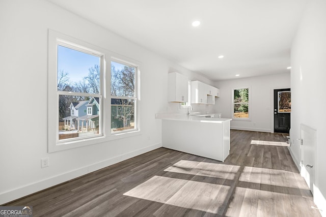 kitchen with kitchen peninsula, sink, white cabinets, and dark hardwood / wood-style floors