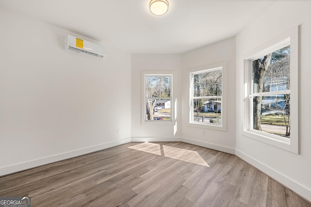 empty room with a wall mounted air conditioner and light hardwood / wood-style flooring