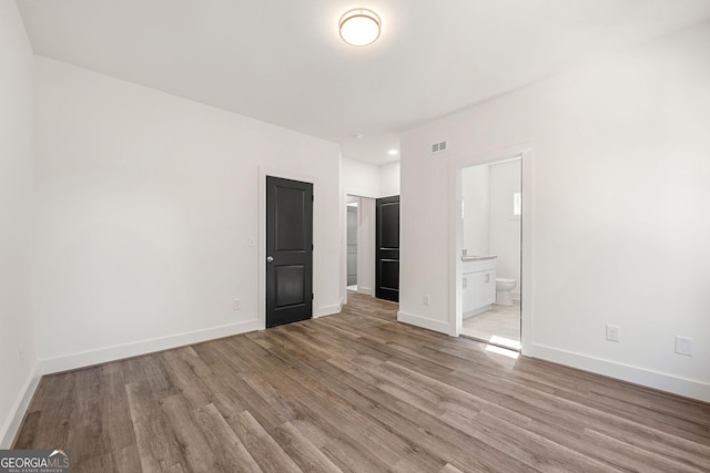 unfurnished bedroom featuring light hardwood / wood-style floors and connected bathroom