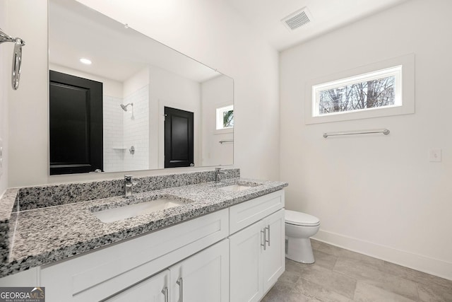 bathroom featuring a tile shower, vanity, and toilet