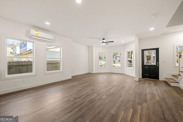 unfurnished living room featuring a wealth of natural light, ceiling fan, dark hardwood / wood-style flooring, and a wall unit AC