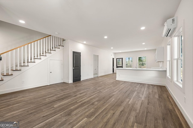 unfurnished living room with dark hardwood / wood-style flooring and an AC wall unit