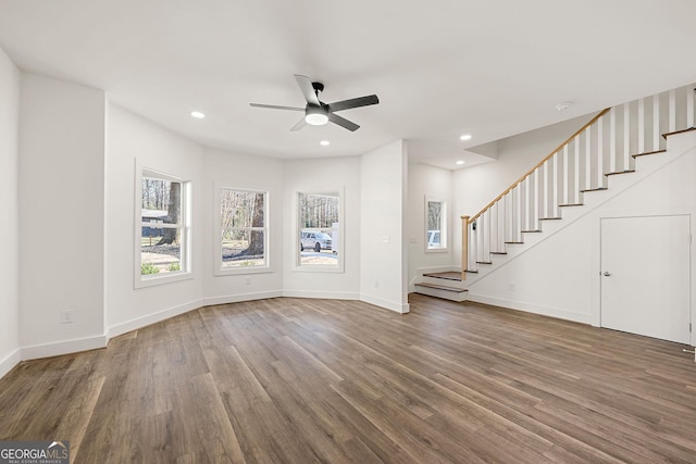 unfurnished living room featuring ceiling fan and dark wood-type flooring