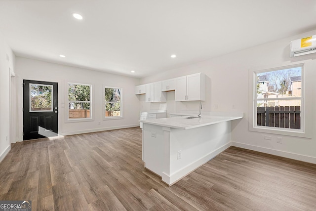 kitchen featuring white cabinets, kitchen peninsula, a healthy amount of sunlight, and light hardwood / wood-style floors