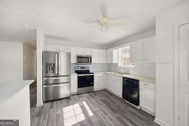 kitchen with appliances with stainless steel finishes, white cabinetry, sink, dark wood-type flooring, and ceiling fan