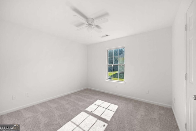 empty room with ceiling fan and light carpet