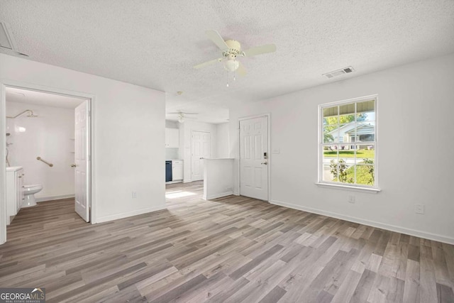 unfurnished bedroom with light hardwood / wood-style floors, ceiling fan, connected bathroom, and a textured ceiling