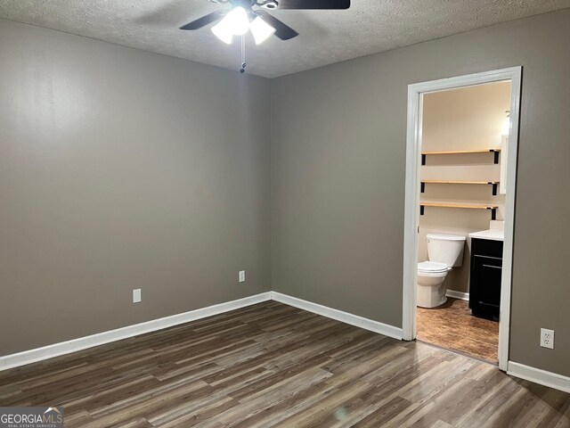 unfurnished bedroom with ceiling fan, dark hardwood / wood-style floors, a spacious closet, and a textured ceiling