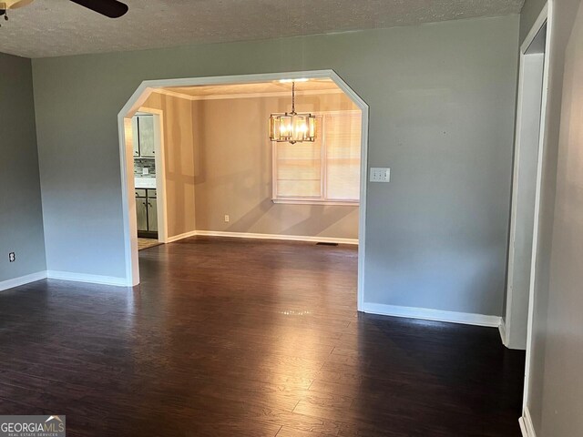 spare room featuring ceiling fan with notable chandelier, a textured ceiling, and dark hardwood / wood-style floors