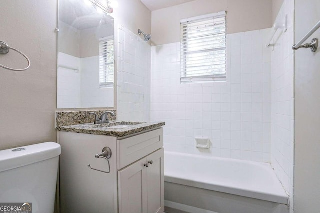 full bathroom featuring tiled shower / bath combo, vanity, and toilet